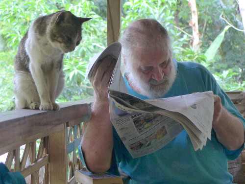 Image of man and a cat reading a
        newspaper