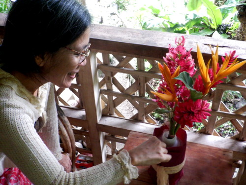 Image of woman with flowers on
        tropical balcony
